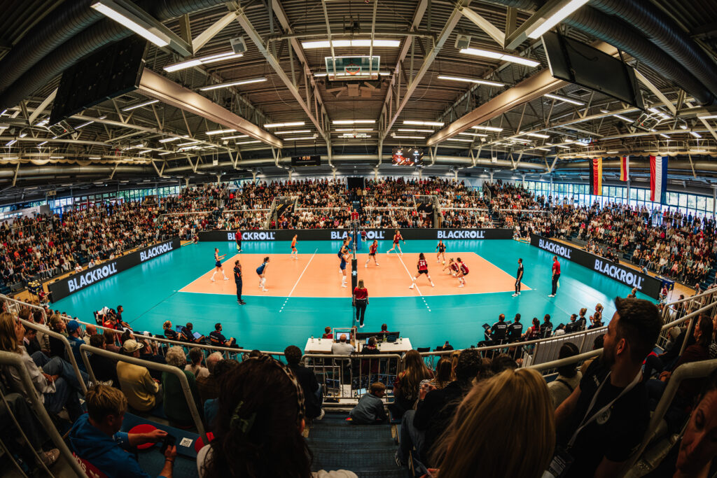 Volleyballfeld mit LED-Banden in einer voll besetzten Halle.
